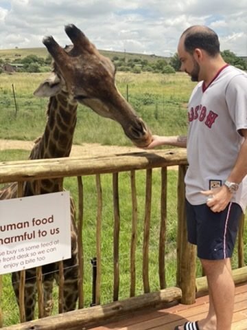 Tiago Lopes alimentando uma girafa na mão