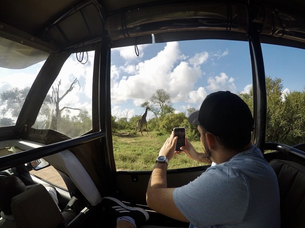 Tiago Lopes fotografando uma girafa de dentro do jipe