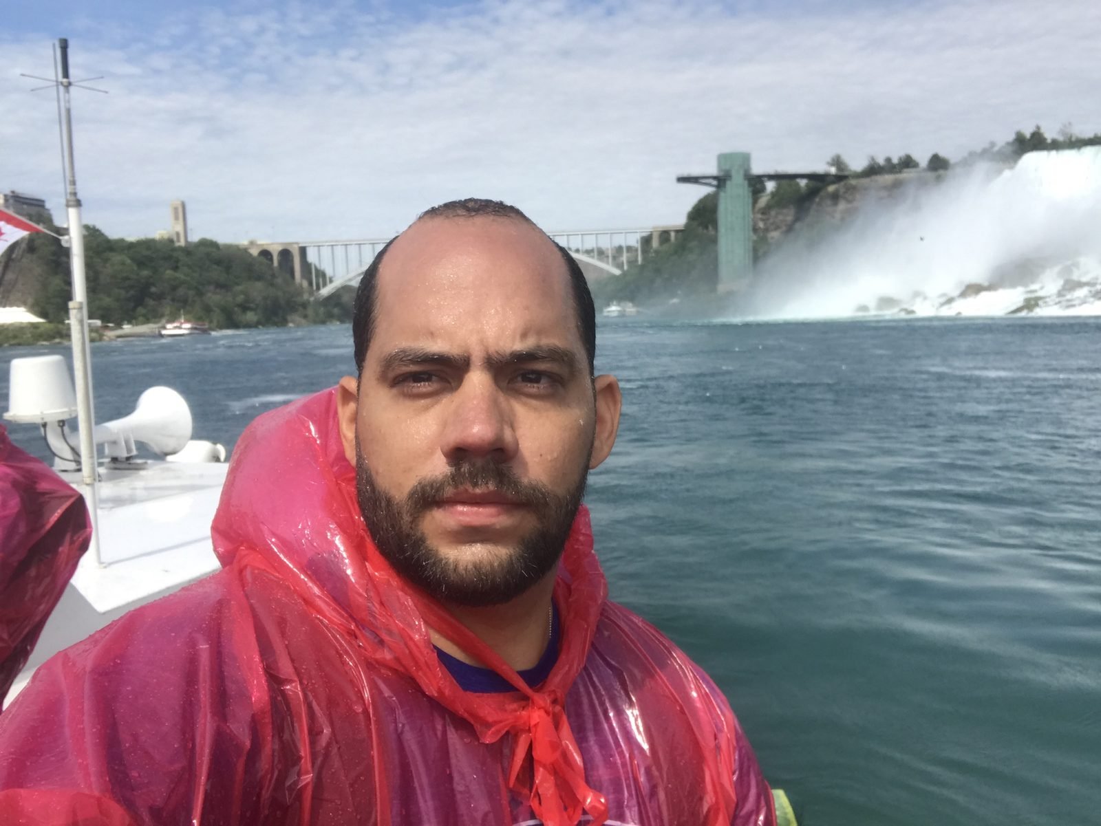 Tiago Lopes de capa de chuva vermelha a bordo do barco, com as quedas ao fundo