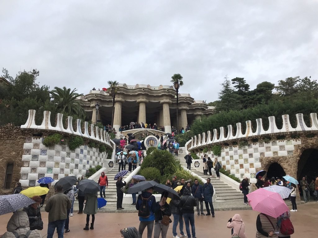 Escadaria do Park Güell, em Barcelona, com visitantes de guarda-chuva