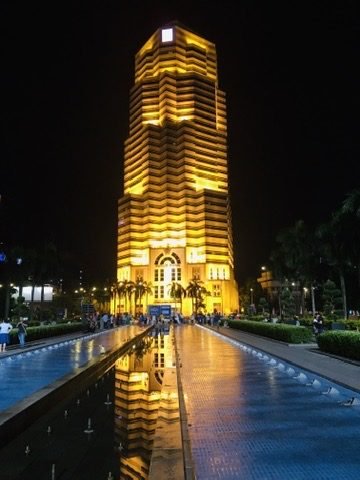 Prédio iluminado em dourado à noite, refletido em um espelho d'água