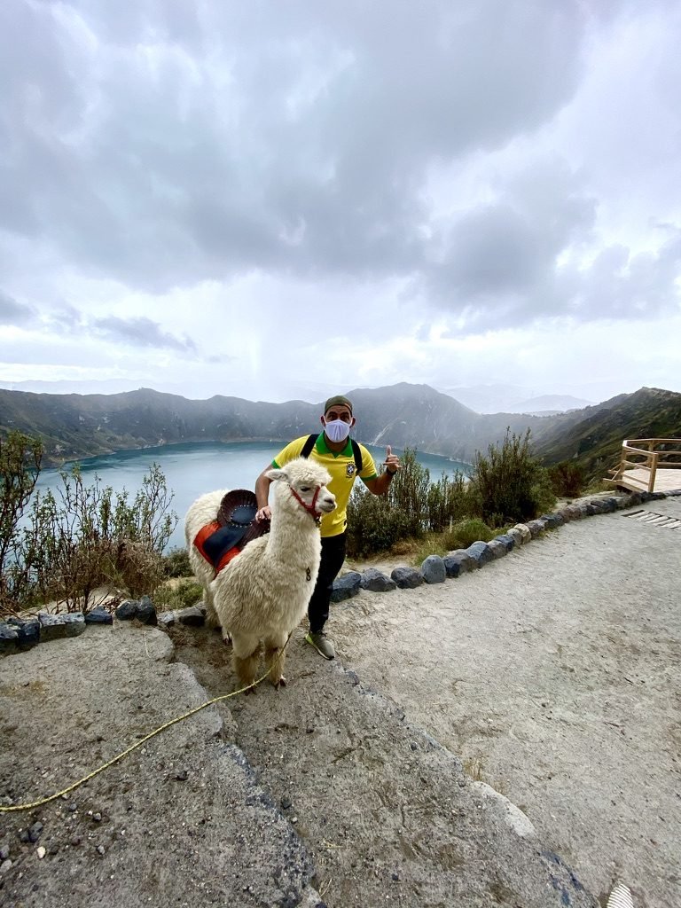 Tiago Lopes ao lado de uma alpaca na borda da cratera do Quilotoa