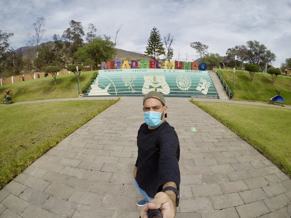 Tiago Lopes em selfie diante do letreiro Mitad del Mundo, latitude 0°