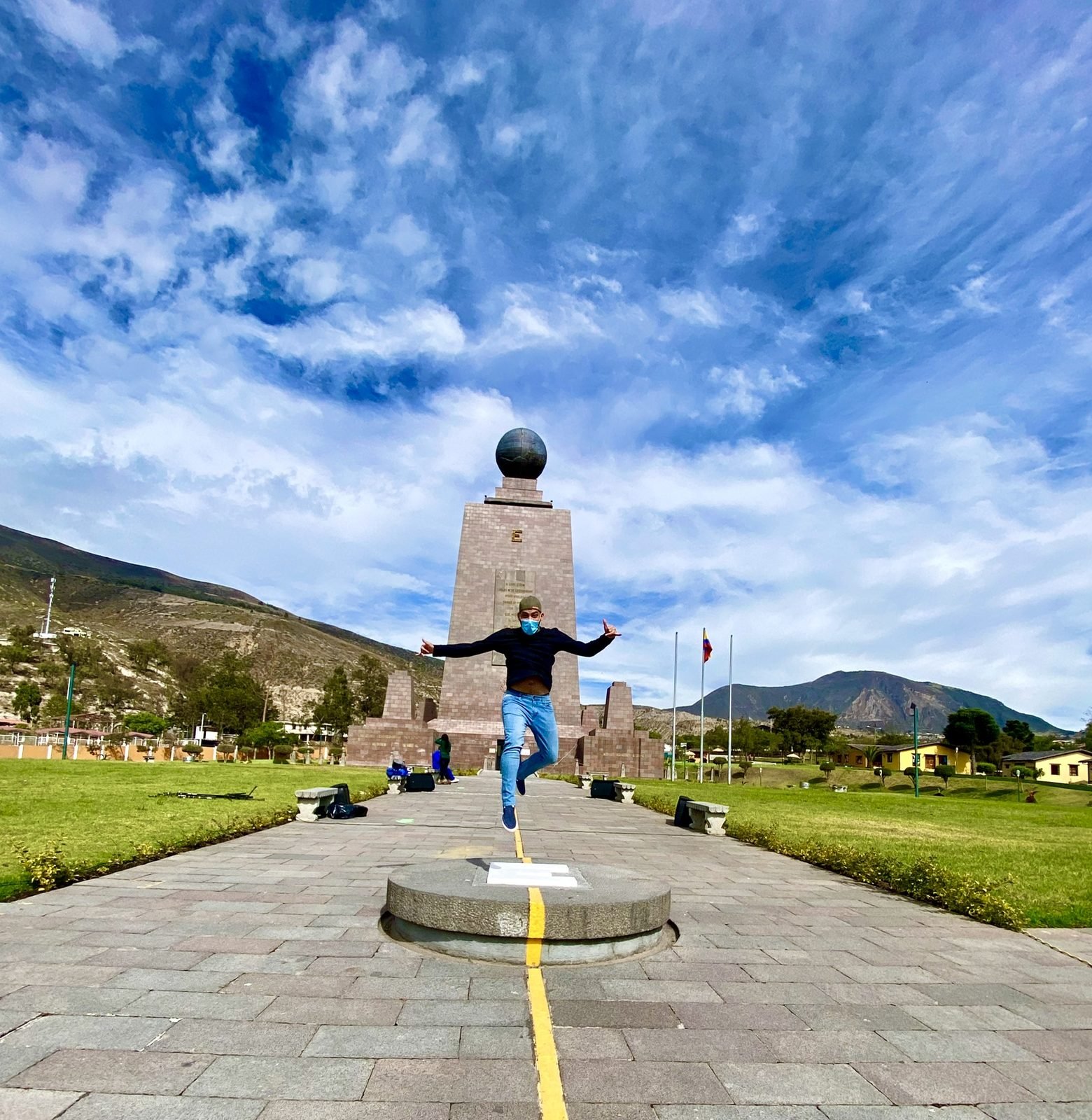 Tiago Lopes saltando sobre a linha amarela do Equador, diante do monumento Mitad del Mundo