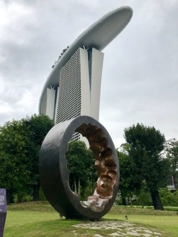 Escultura circular em um gramado, com o Marina Bay Sands atrás