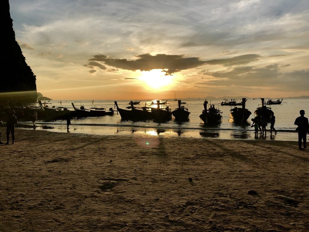 Barcos long-tail ancorados na praia ao pôr do sol