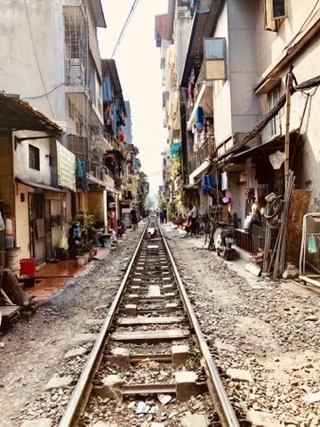 Trilhos de trem passando entre casas, na Rua do Trem de Hanói